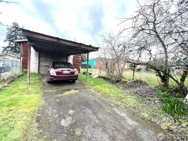 view of parking / parking lot with a carport, driveway, and fence