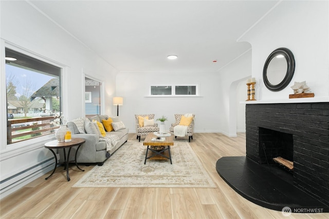 living area with baseboards, ornamental molding, a fireplace, wood finished floors, and arched walkways