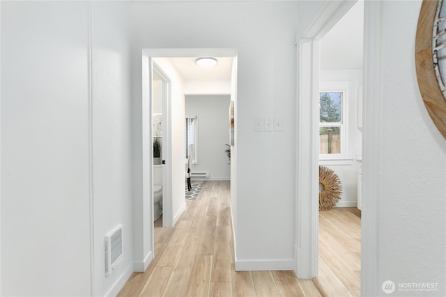 hallway with light wood-type flooring, baseboards, visible vents, and a baseboard radiator