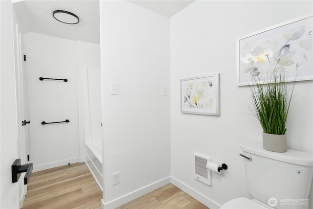 full bathroom featuring baseboards, heating unit, toilet, and wood finished floors