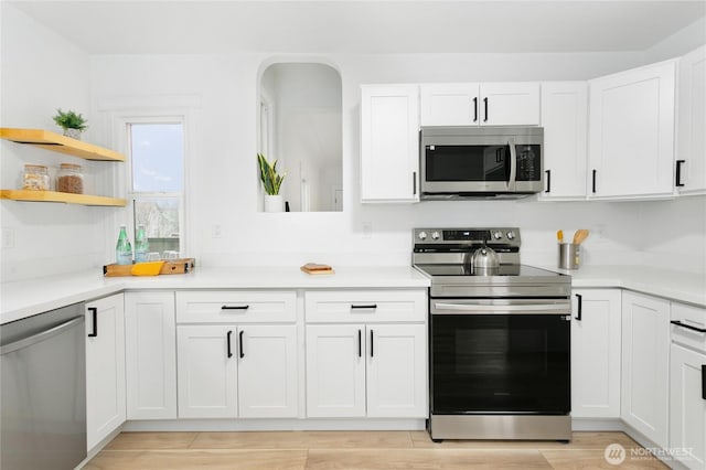 kitchen featuring light wood-type flooring, stainless steel appliances, white cabinets, and light countertops