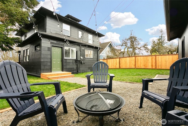 back of property with a lawn, entry steps, an outdoor fire pit, and fence