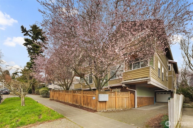 obstructed view of property with driveway, a garage, and a fenced front yard