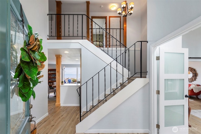 stairway with a notable chandelier, baseboards, and wood finished floors