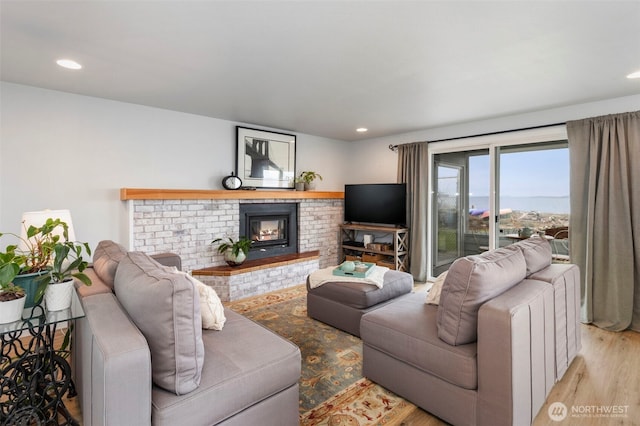living room featuring wood finished floors, a brick fireplace, and recessed lighting