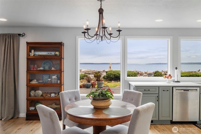dining room with a water view, light wood-type flooring, a chandelier, and recessed lighting