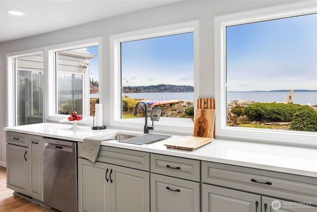 kitchen featuring a water view, gray cabinets, and dishwasher