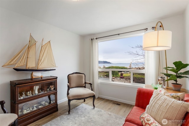 sitting room featuring visible vents, baseboards, and wood finished floors