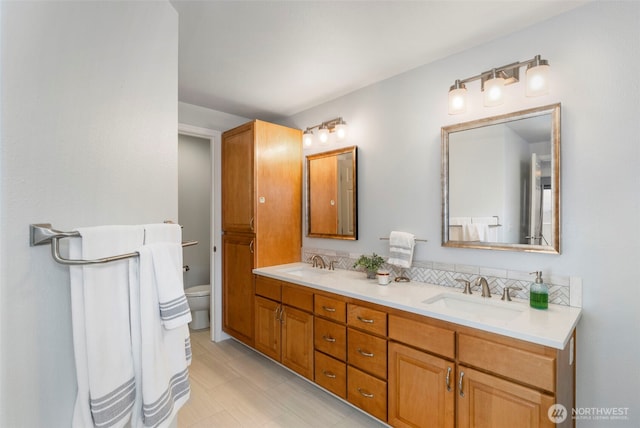 bathroom featuring toilet, double vanity, and a sink