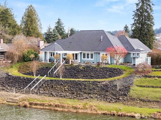 view of front of home with stairs, a water view, and a chimney