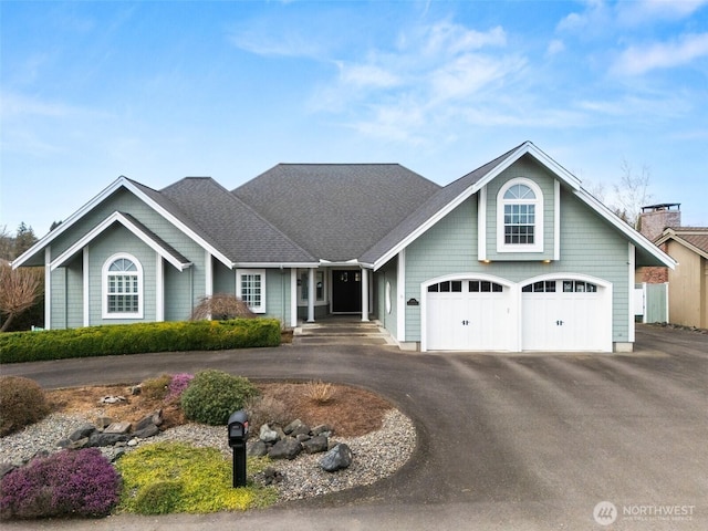 view of front of property with an attached garage, driveway, and roof with shingles