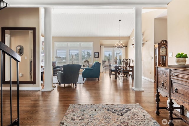 interior space featuring decorative columns, wood finished floors, baseboards, and a chandelier