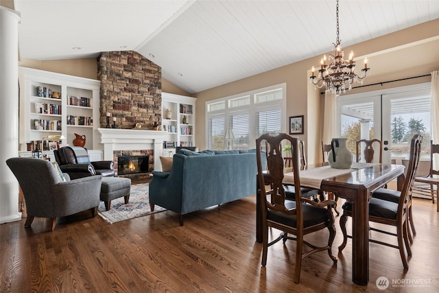 dining area featuring plenty of natural light, a stone fireplace, dark wood-type flooring, and vaulted ceiling