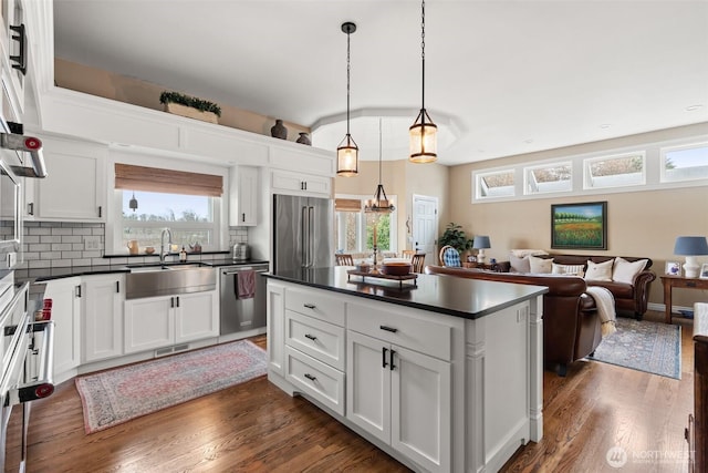 kitchen featuring dark countertops, backsplash, appliances with stainless steel finishes, and a sink