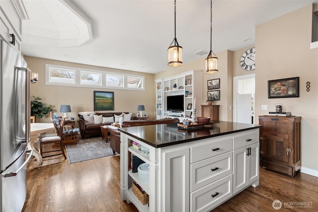 kitchen featuring stainless steel fridge, dark countertops, dark wood-style flooring, and white cabinetry