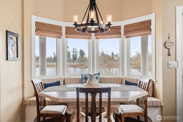 dining space featuring breakfast area, an inviting chandelier, and a water view