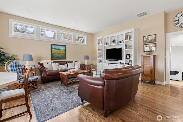 living area featuring visible vents, baseboards, and wood finished floors