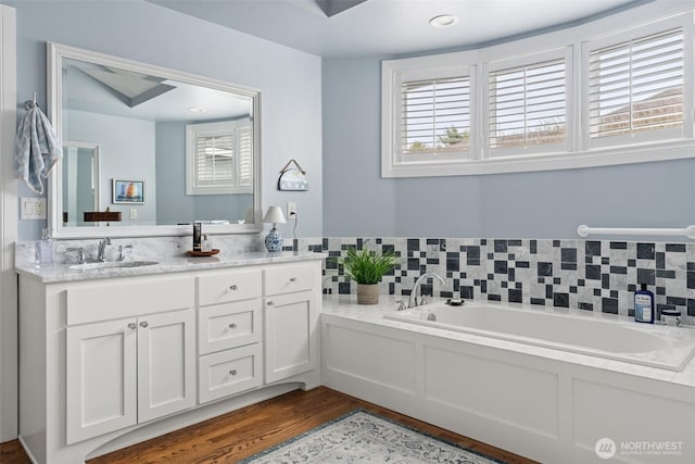 bathroom with wood finished floors, a bath, and vanity