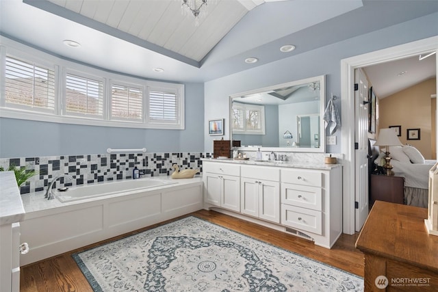 full bath with lofted ceiling, recessed lighting, wood finished floors, a bath, and vanity