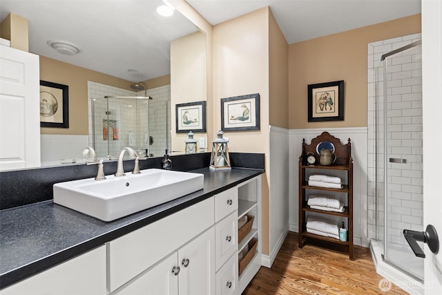 full bath with wainscoting, wood finished floors, a stall shower, and vanity