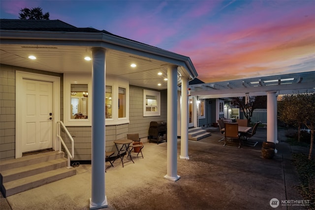 patio terrace at dusk with entry steps, outdoor dining space, and a pergola