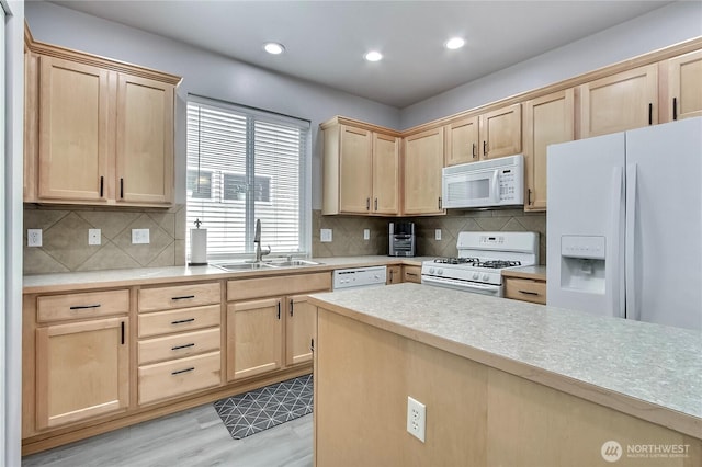 kitchen featuring light brown cabinetry, white appliances, light countertops, and a sink