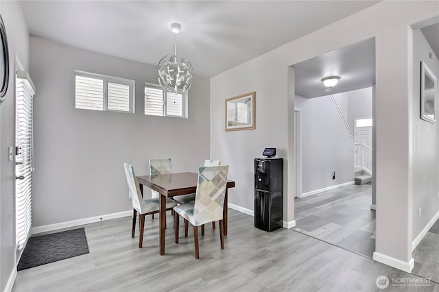 dining area with stairway, wood finished floors, baseboards, and a chandelier