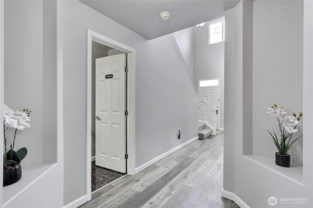 hall with stairway, wood finished floors, and baseboards