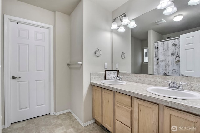 full bathroom with double vanity, baseboards, visible vents, and a sink