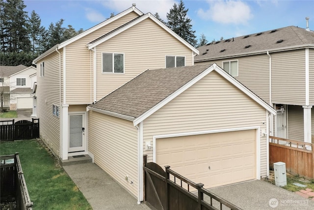 view of front facade featuring driveway, a shingled roof, a garage, and fence