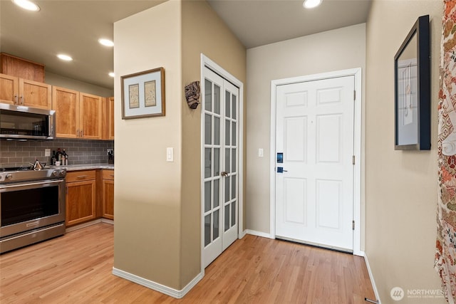 kitchen featuring tasteful backsplash, baseboards, light wood-type flooring, recessed lighting, and appliances with stainless steel finishes