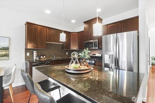 kitchen featuring tasteful backsplash, wood finished floors, stainless steel appliances, and a sink