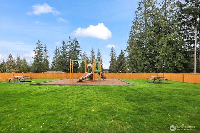 communal playground featuring a yard and fence