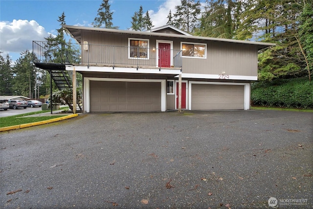 view of front of home featuring aphalt driveway, an attached garage, and stairs