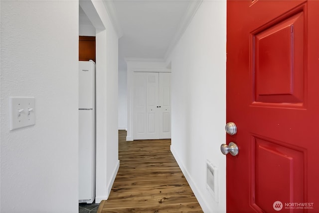 hall featuring visible vents, baseboards, wood finished floors, and crown molding