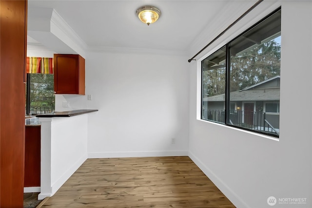 unfurnished dining area with crown molding, wood finished floors, and baseboards