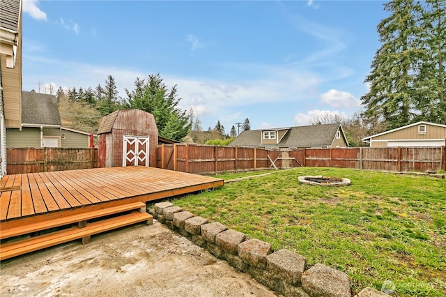 view of yard featuring a fire pit, a fenced backyard, a shed, and an outdoor structure