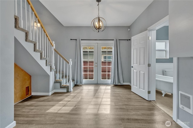 foyer entrance featuring french doors, stairs, baseboards, and wood finished floors