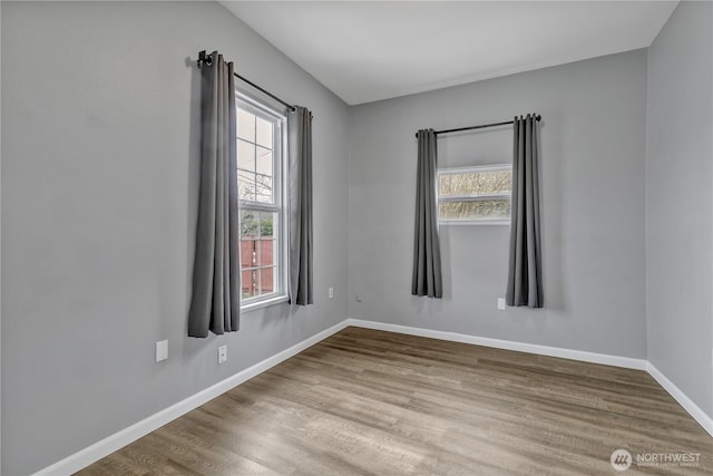 spare room with wood finished floors, baseboards, and a wealth of natural light