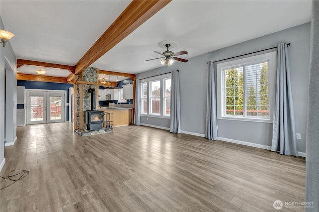 unfurnished living room featuring a wealth of natural light, wood finished floors, and a wood stove