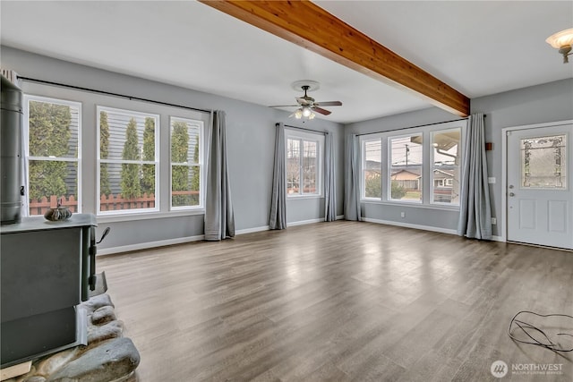 unfurnished living room featuring beamed ceiling, a ceiling fan, baseboards, and wood finished floors