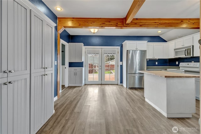 kitchen featuring wooden counters, beamed ceiling, appliances with stainless steel finishes, french doors, and light wood-style floors