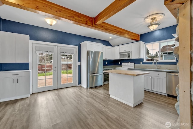 kitchen featuring light wood-style flooring, appliances with stainless steel finishes, french doors, white cabinets, and a sink