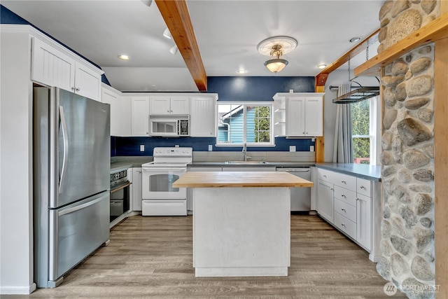 kitchen featuring butcher block countertops, beam ceiling, light wood-style flooring, appliances with stainless steel finishes, and a sink