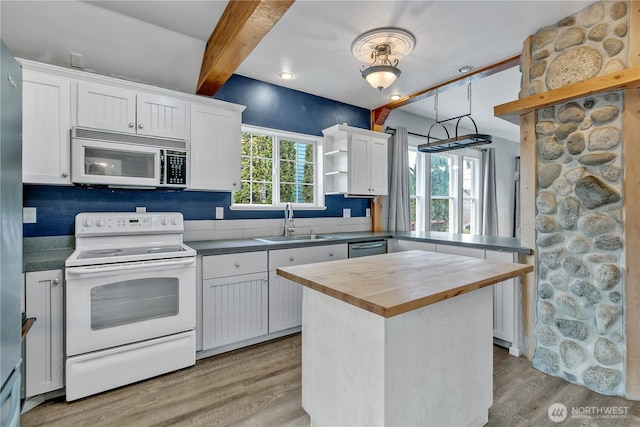 kitchen featuring a sink, butcher block counters, light wood-style floors, stainless steel appliances, and open shelves