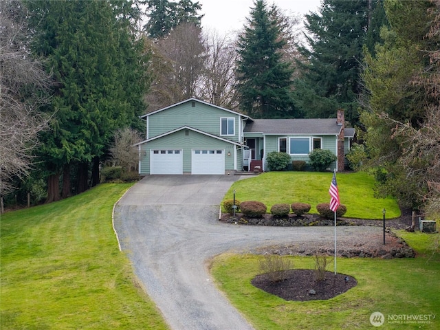 split level home with a chimney, a front lawn, an attached garage, and driveway