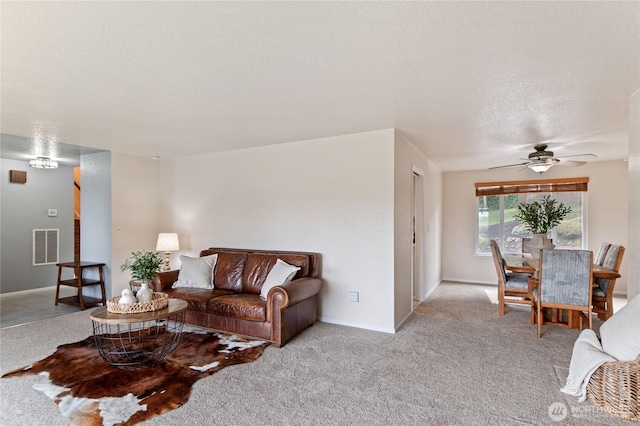 carpeted living room featuring visible vents, baseboards, a textured ceiling, and a ceiling fan