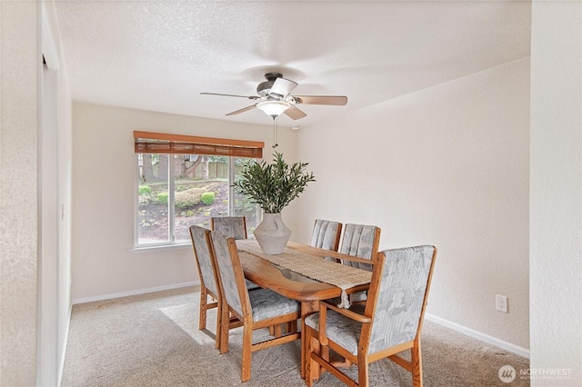 carpeted dining room featuring baseboards, a textured ceiling, and a ceiling fan