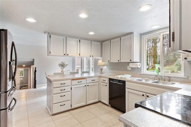 kitchen with a sink, black appliances, a peninsula, and light tile patterned floors