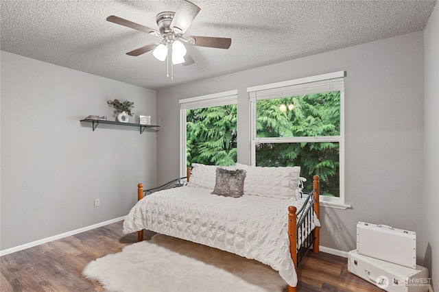 bedroom featuring a ceiling fan, wood finished floors, baseboards, and a textured ceiling